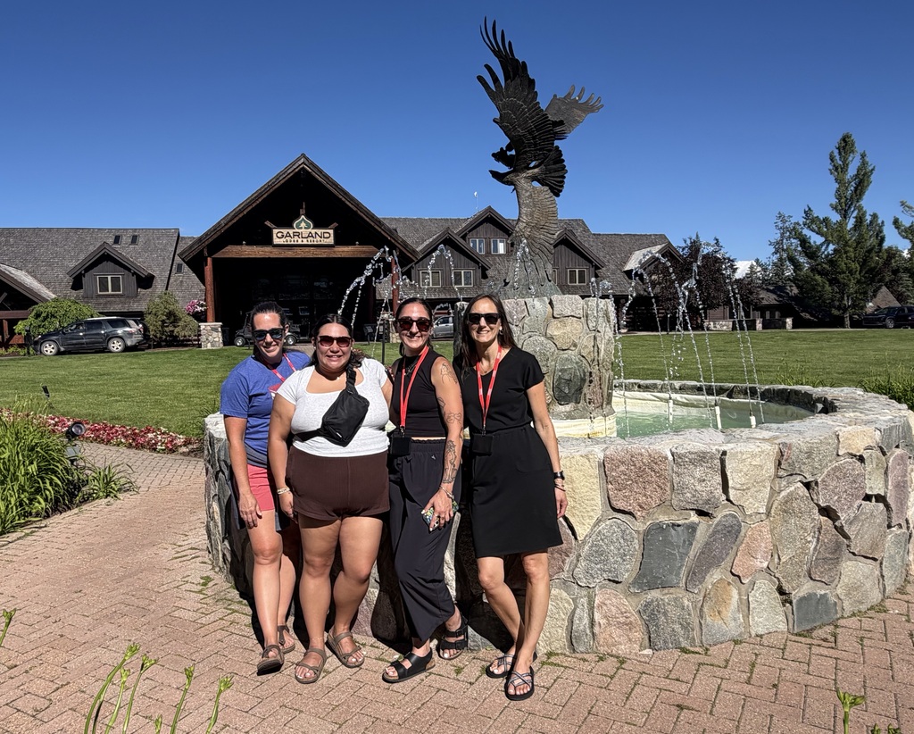 picture of four women standing in front of fountain with an eagle statue on top