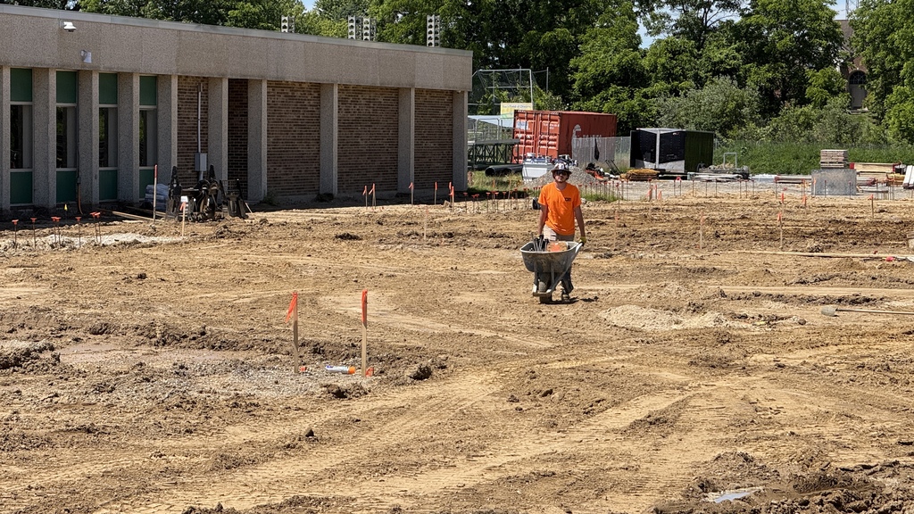 Photo of construction crews working on large site with brown dirt and heavy machinery