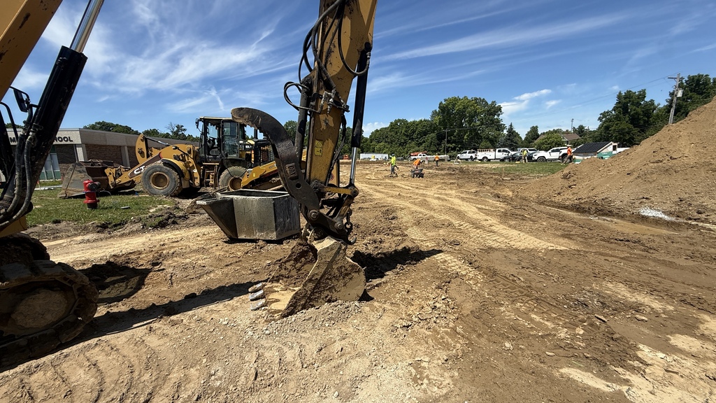 Photo of construction crews working on large site with brown dirt and heavy machinery