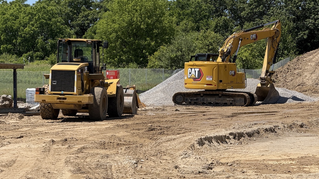 Photo of construction crews working on large site with brown dirt and heavy machinery