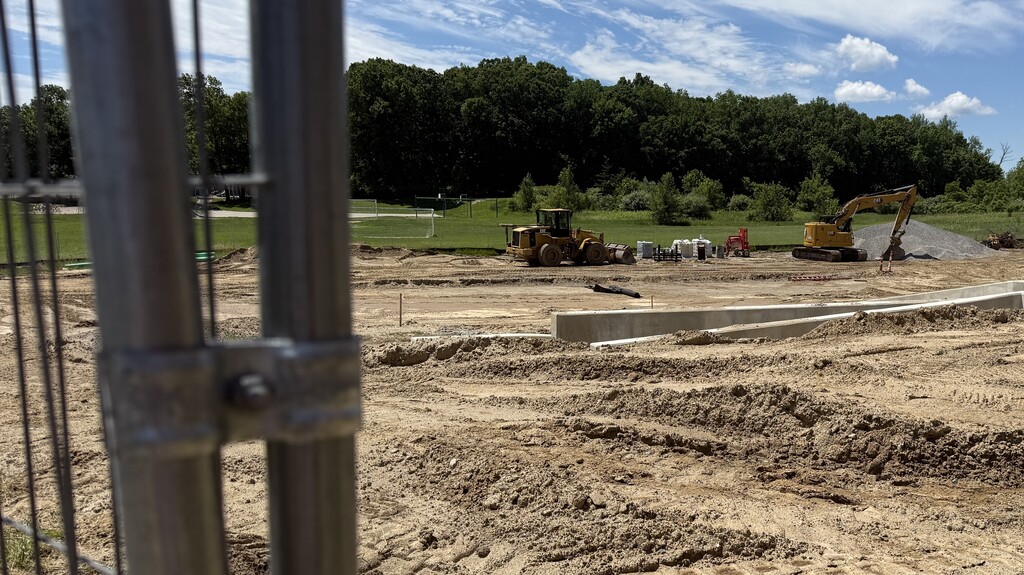 Photo of construction crews working on large site with brown dirt and heavy machinery