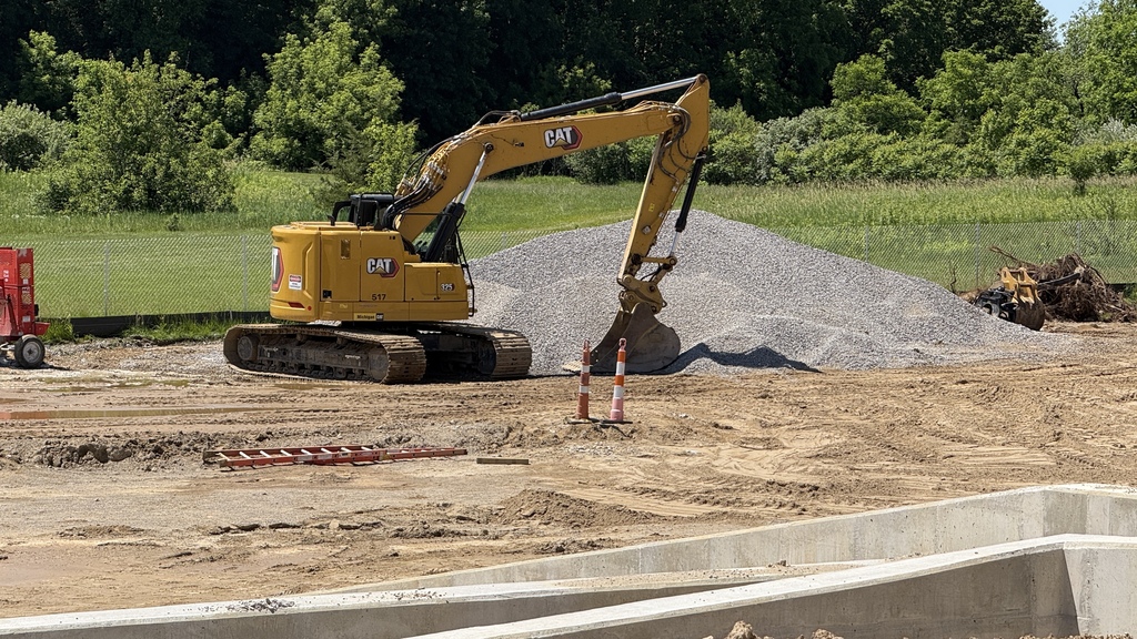 Photo of construction crews working on large site with brown dirt and heavy machinery
