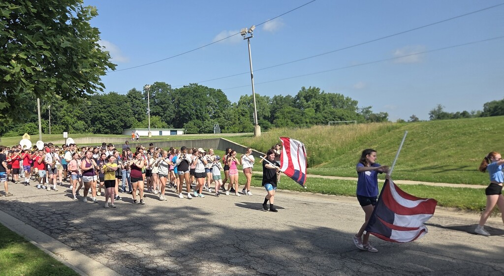 Photo of marching band playing music while walking down street