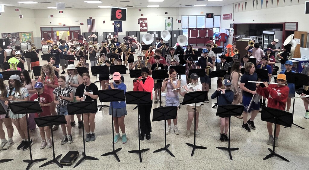 Photo of band members playing various instruments in a classroom setting