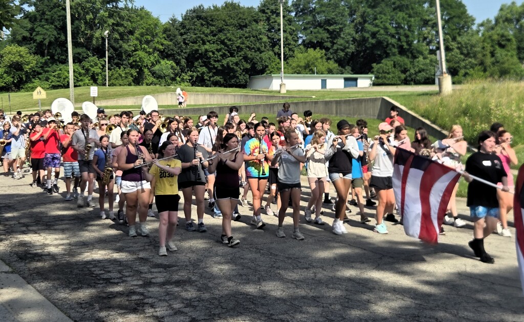 Photo of marching band playing music while walking down street