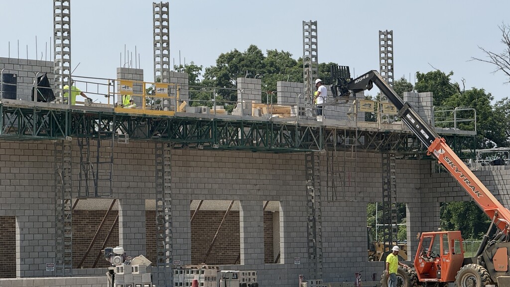 Photo of large brick wall on construction site with men working on top