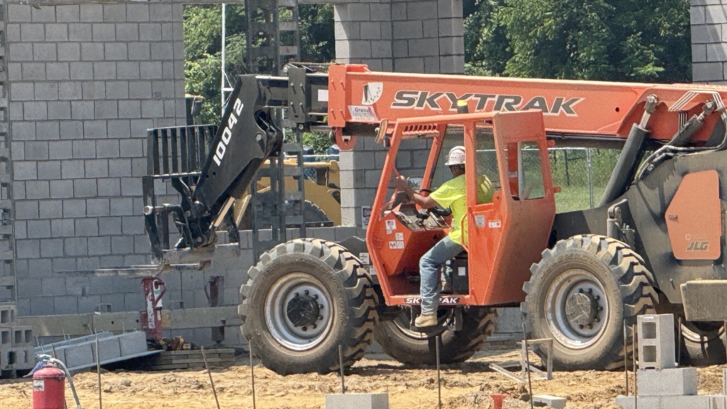 man sitting on large piece of construction equipment at construction site