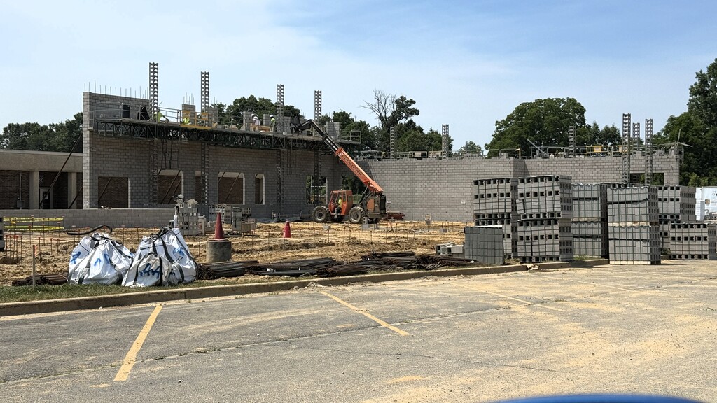 Photo of large brick wall on construction site with men working on top