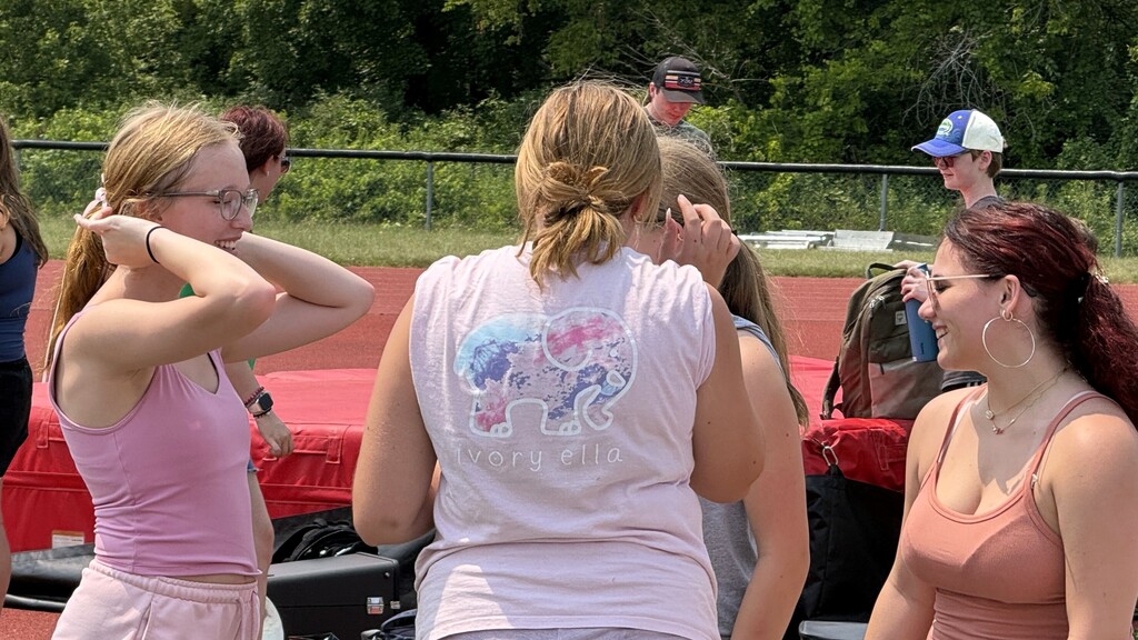 photo of marching band members standing and talking with each other