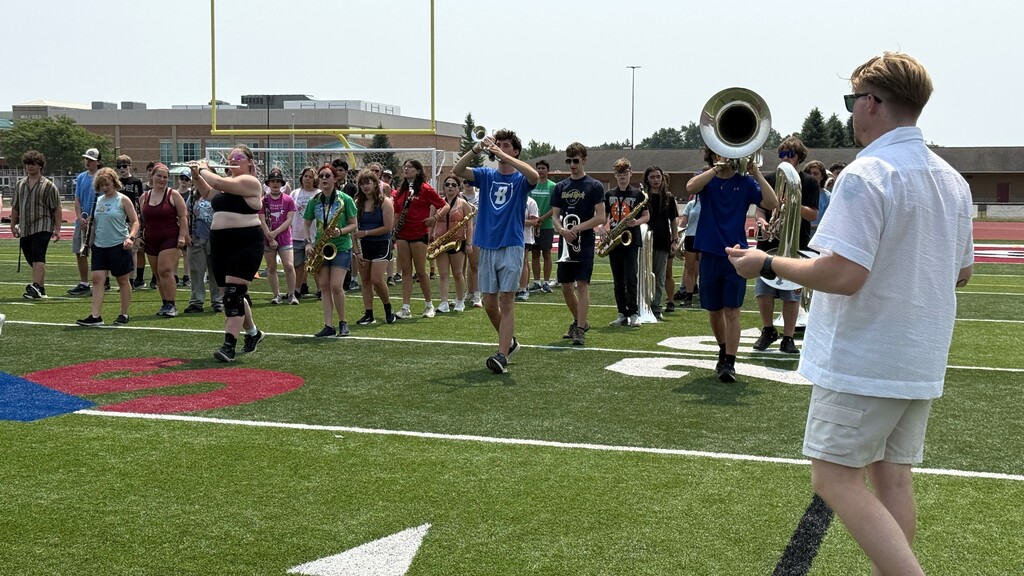 photo of marching band members marching on the football field