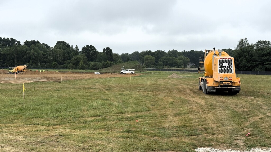 Photo of cement truck parked on a grass field near a constuction site
