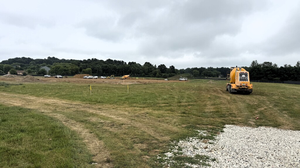 Photo of cement truck parked on a grass field near a constuction site