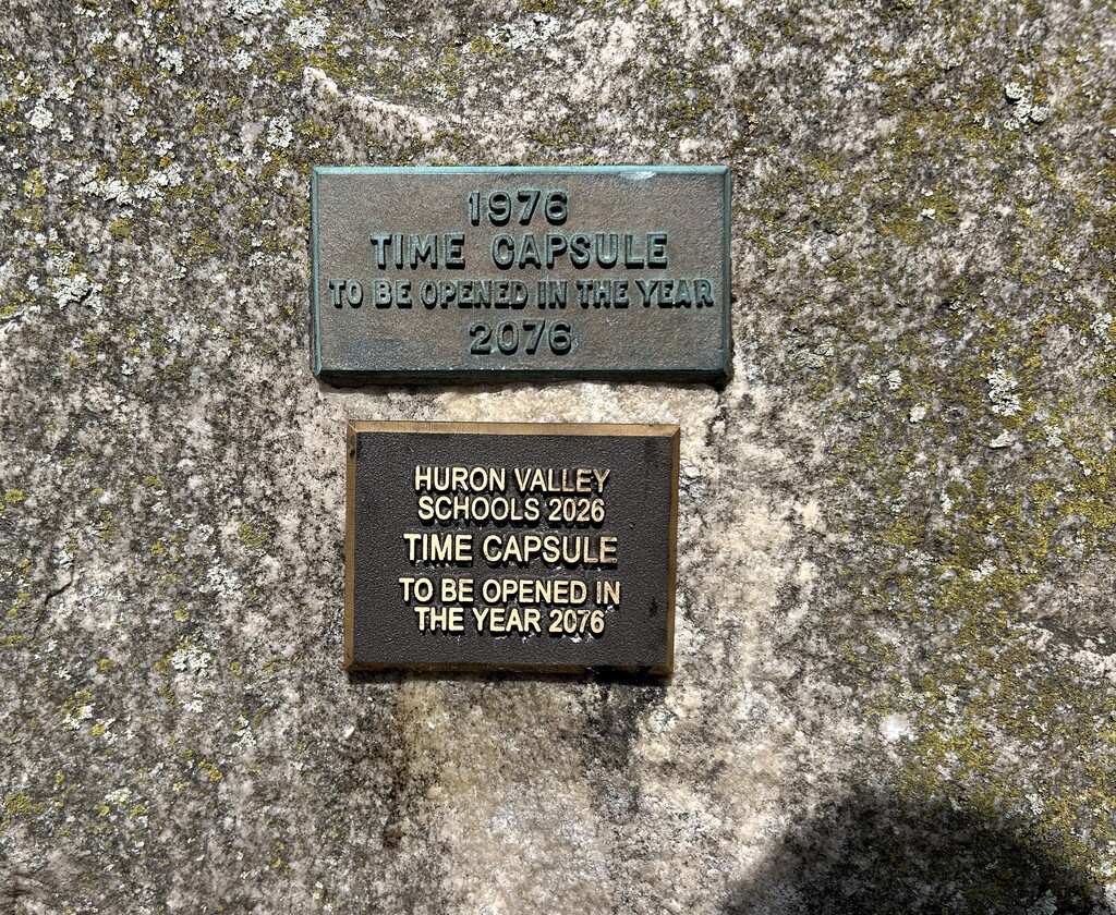 Photo of two plaques attached to a large boulder that read " time capsule to be opened in 2076"