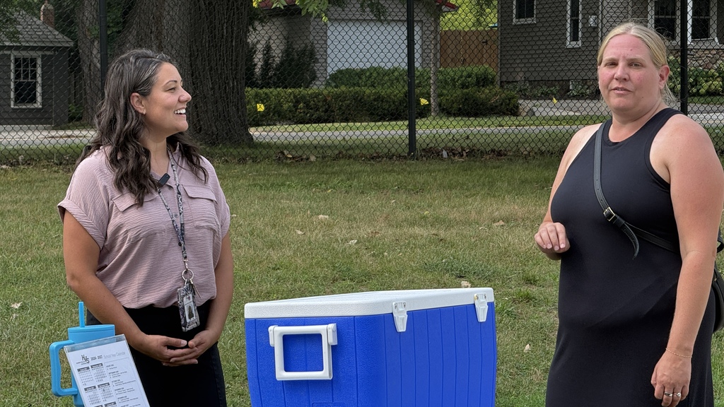 Two women smiling and talking outside near a cooler