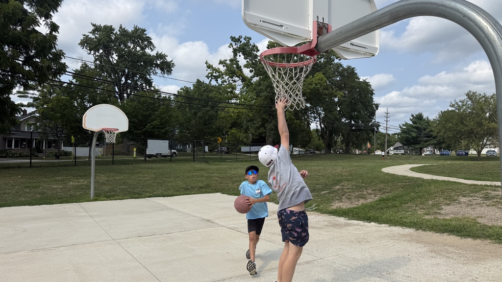 young boys playing basketball outdoors