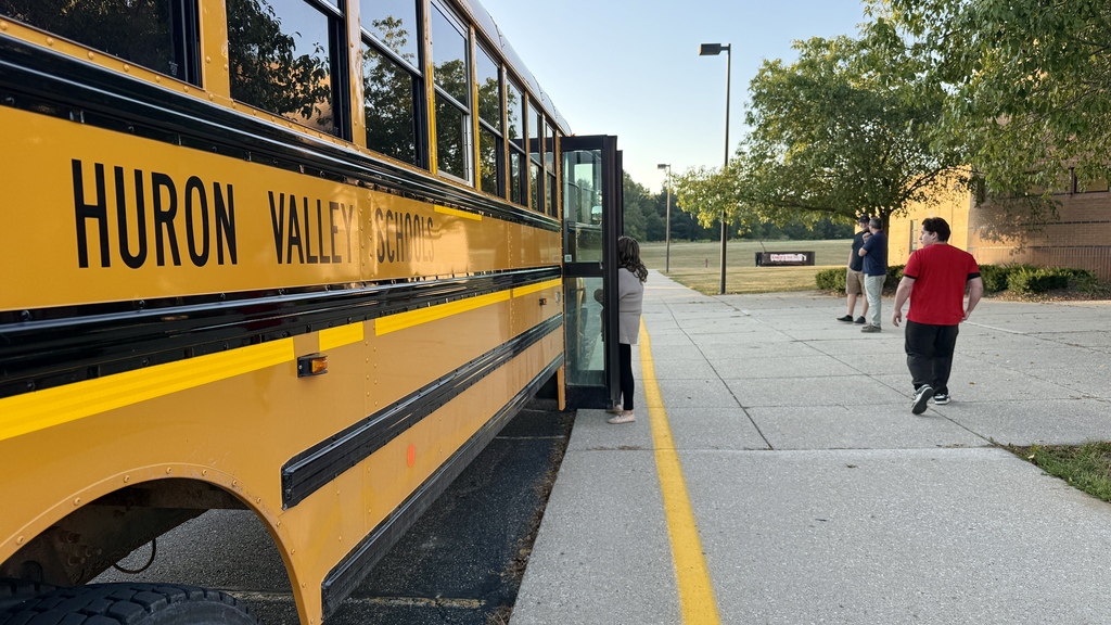 photo of school bus parked out front of a school 