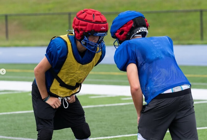 Photo of two boys in football uniforms lining up and doing drills