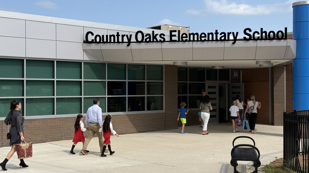 Students and parents walking into the front door of a school 