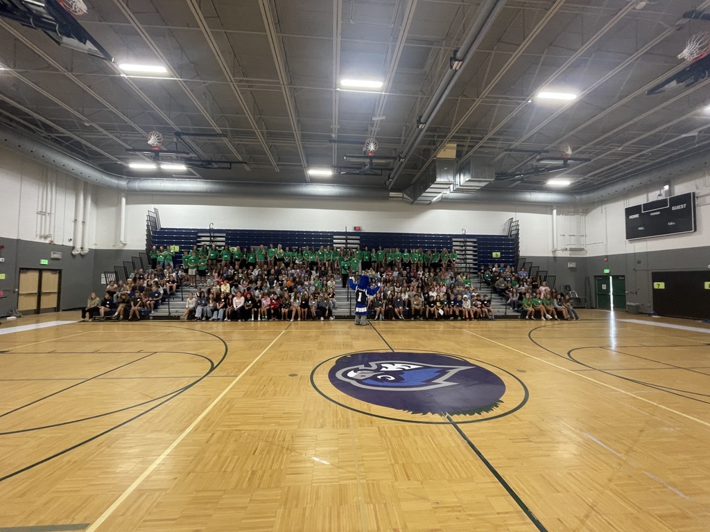 Wide shot photo of kids sitting on bleachers inside a gym