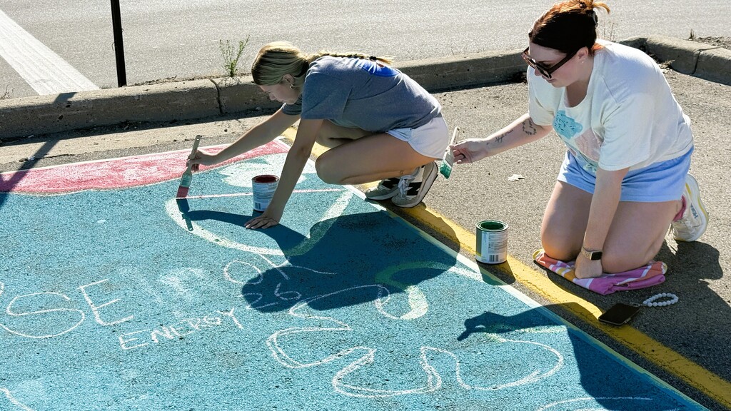 Senior girls painting on the ground in parking lot
