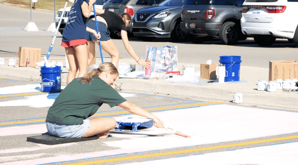Senior girl painting on the ground in parking lot