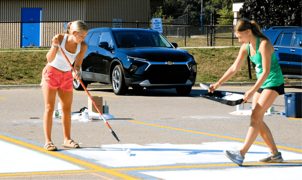Senior girls painting on the ground in parking lot