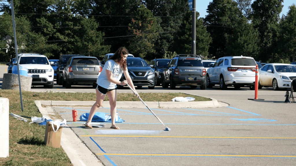 Senior girl painting on the ground in parking lot