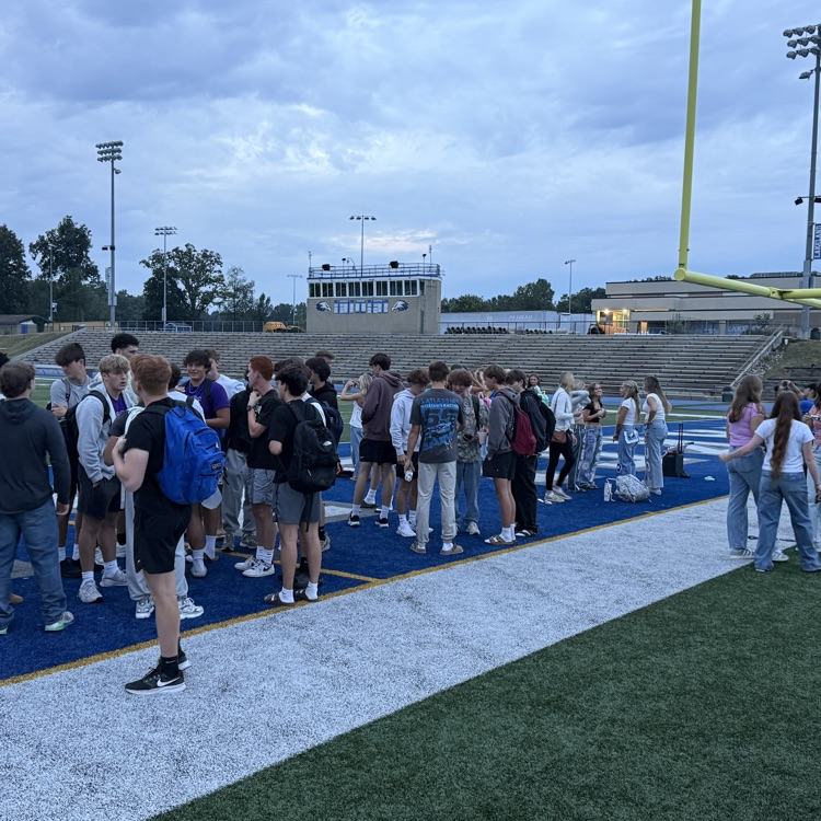 dozens of students gathering on football field