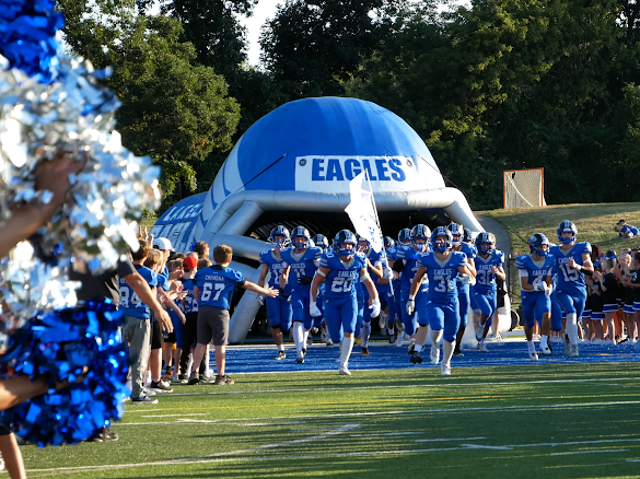 photo of football players running out of a tunnel made to look like a football helmet