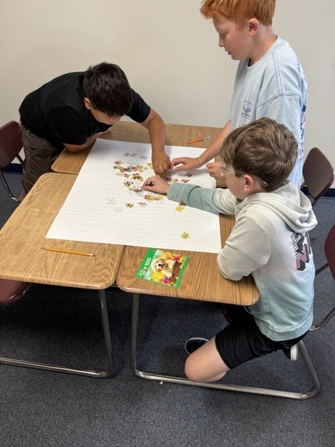 Students work as a group to solve a puzzle on their desks.