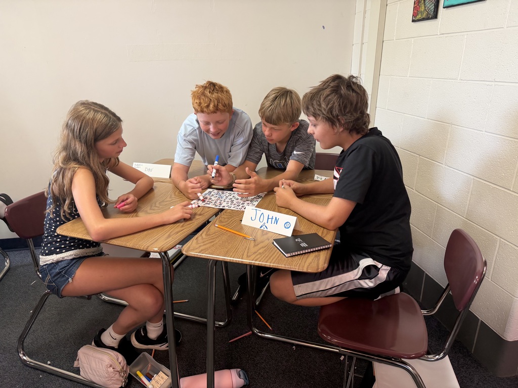 Students work as a group to solve a puzzle on their desks.