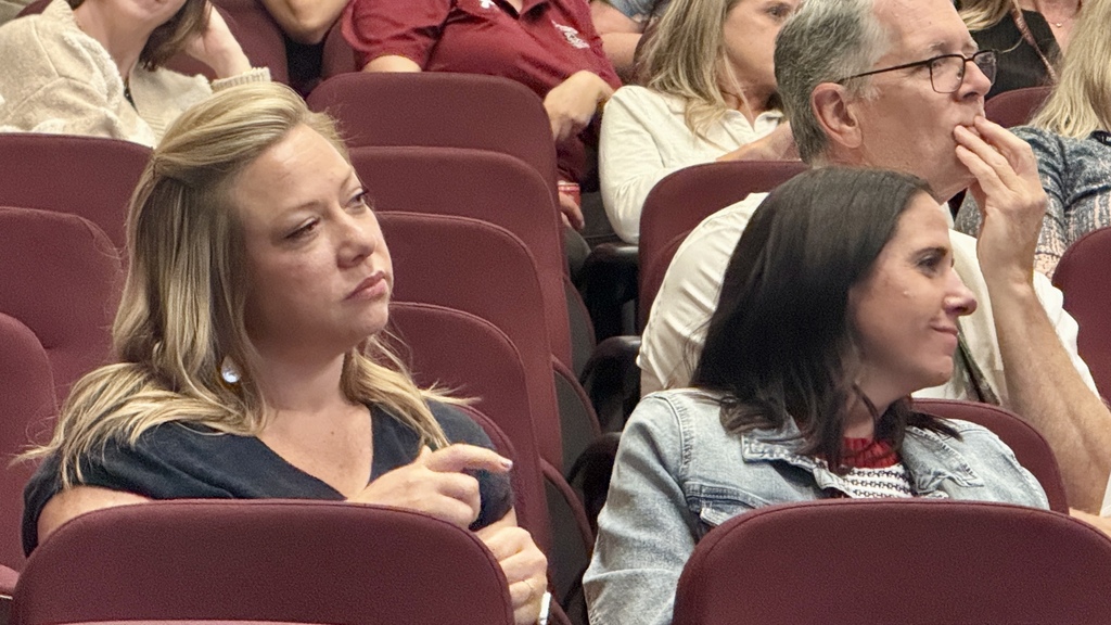 Two teachers sitting in an auditorium listening 
