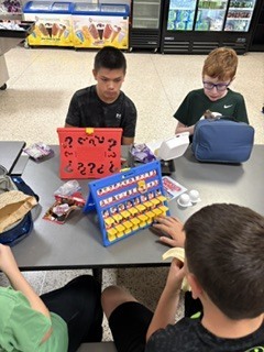 students sitting at cafeteria tables playing games