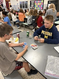 students sitting at cafeteria tables playing games