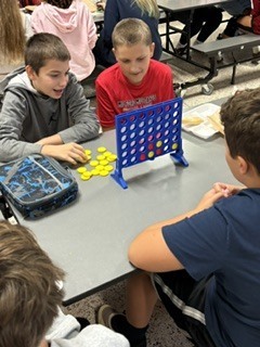 students sitting at cafeteria tables playing games