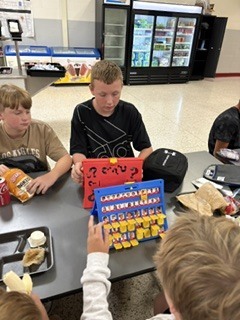 students sitting at cafeteria tables playing games