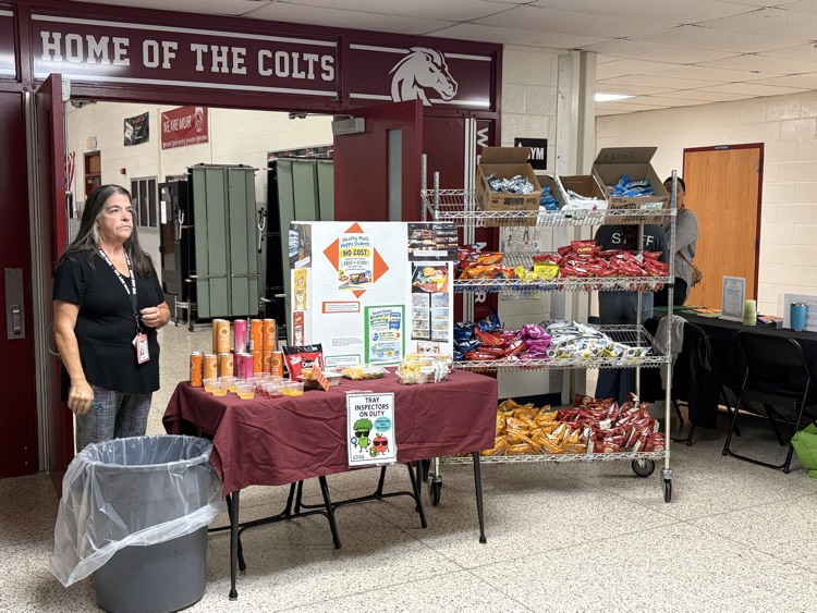 Kitchen staff stand at a table with information about school meals