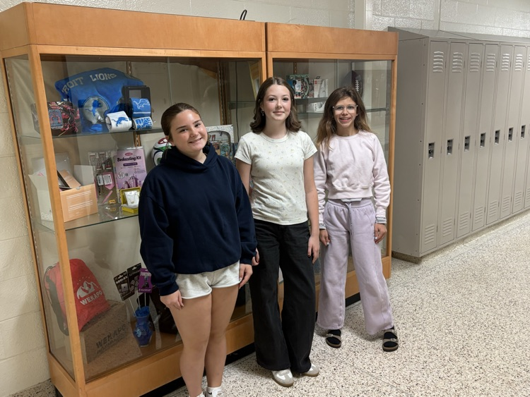 3 prize winning students in front of case of prizes