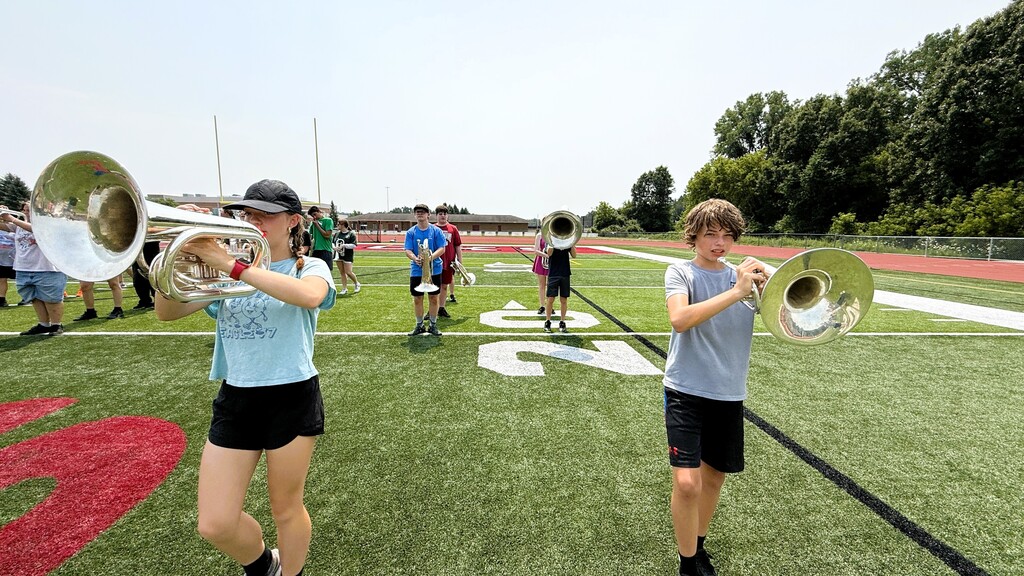 Several band members marching on a football field for practice.