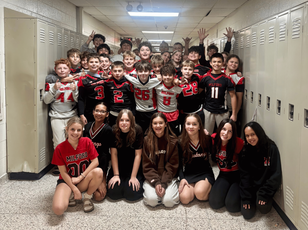 A group of students in red, white, and black football and cheer gear for Mustangs
