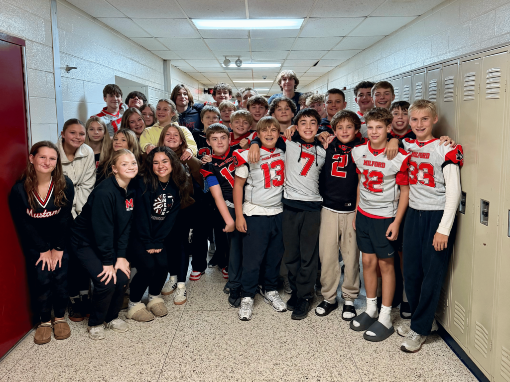 A group of students in red, white, and black football and cheer gear for Mustangs
