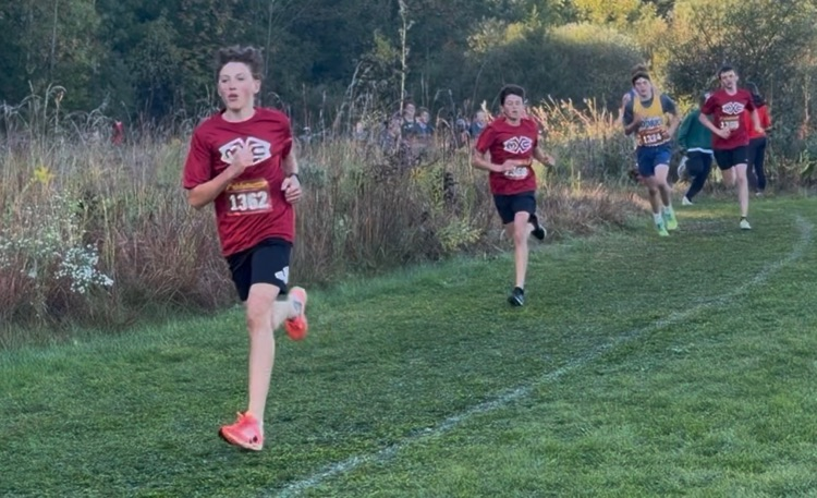 cross country runners wearing maroon Muir shirt running on trail