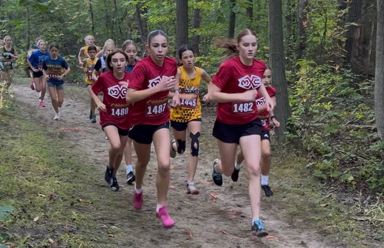 cross country runners wearing maroon Muir shirt running on trail