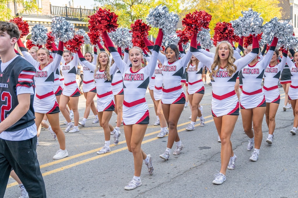 Photo of several cheerleaders walking down a street during a parade