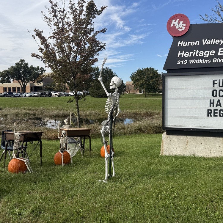 skeletons set up on the grass out front of a school.