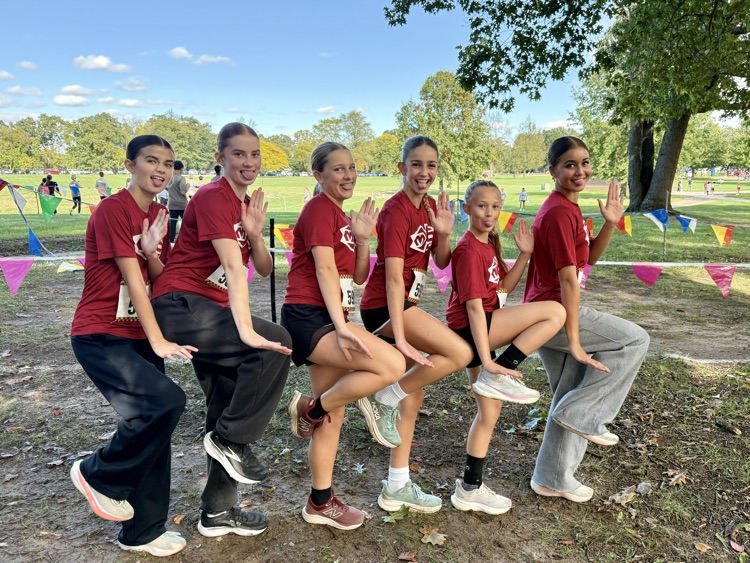 group of cross country runners pose with one leg up