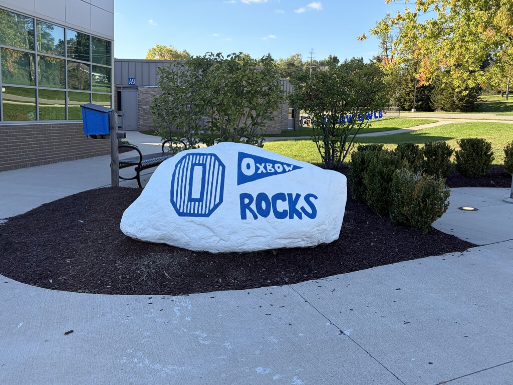 White painted Rock with O in blue and the words Oxbow Rocks painted in blue