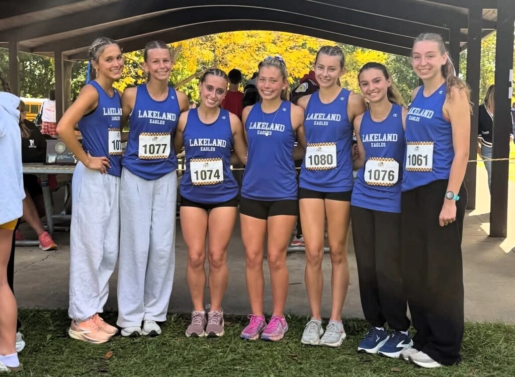 girl high school cross country team in blue uniforms smiling and posing for a photo
