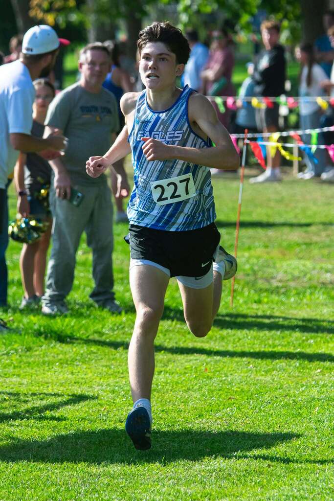 Male high school cross country member running in a race outdoors
