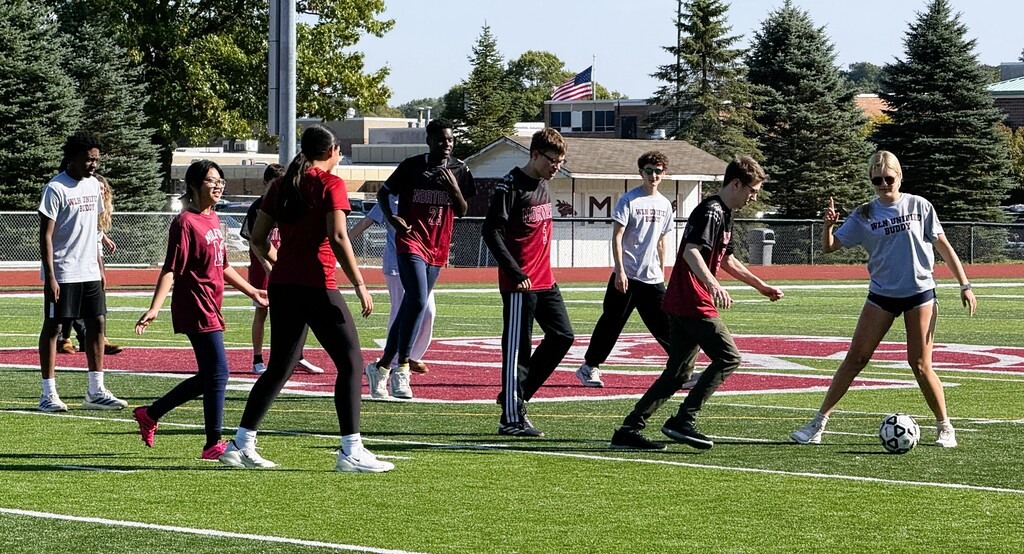 Several soccer players maneuvering for a ball on a field